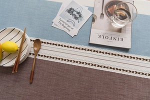 Close-up of Nordic tablecloth featuring leaf embroidery, tassel fringe, and linen texture