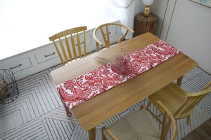 Detail of red and white vintage floral table runner on a light wooden dining table