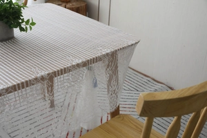Détail de la nappe en dentelle blanche avec motifs floraux et bords en cils délicats