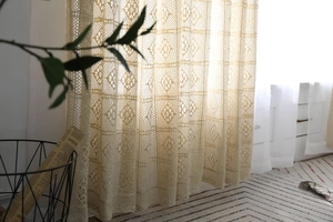 Détail d'un rideau en dentelle crochetée vintage avec motifs floraux creux et bords festonnés
