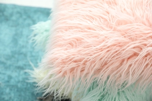 Close-up of soft pink faux sheepskin pillow cover with long plush texture and smooth fur