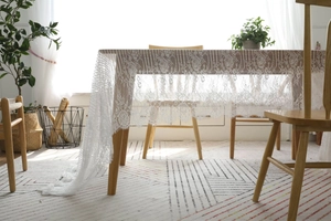 Vue détaillée de la nappe en dentelle blanche avec motifs floraux et bordure drapée