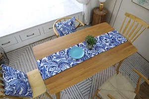 Close-up of blue floral table runner and matching pillows in a rustic wooden dining setting