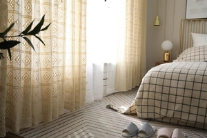 Détail du rideau en dentelle crochet beige vintage avec motifs floraux et lumière douce