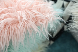 Macro detail of soft faux sheepskin long fur texture on a pink plush pillow cover