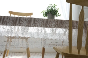 Détail de la nappe en dentelle blanche avec motifs de roses et franges en cils délicats