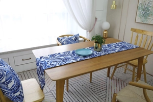 Detailed close-up of blue paisley table runner and matching pillows on a wooden dining table