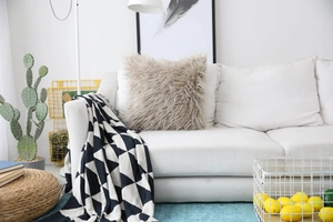 Close-up of soft faux fur pillow and geometric knit blanket on white sofa