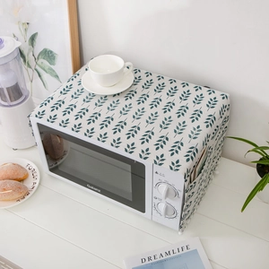 Linen microwave dust cover with blue leaf print and storage pockets on white table