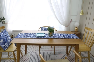 Detail view of blue and white floral table runner and matching cushion on wooden table