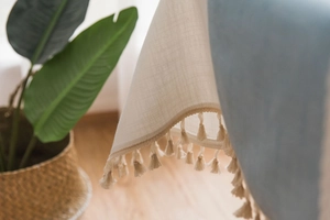 Close-up of cream textured linen tablecloth with elegant fringe tassels and woven detail