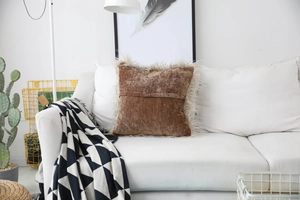 Detail view of brown velvet cushion cover with white faux sheepskin fur trim on a sofa