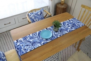 Close-up of blue floral table runner and matching pillow on a rustic wood dining table