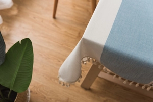 Detailed macro view of Nordic linen blend tablecloth with blue stitching and fringe tassels