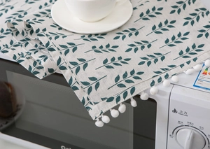 Linen dust cover with green leaf patterns and white pom-poms for microwave decoration