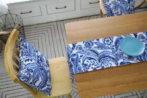 Close-up of blue floral paisley table runner and chair cushions in a rustic dining setting