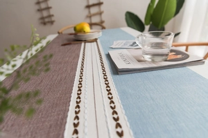 Detail of Nordic table runner with leaf embroidery and tassels on faux linen fabric