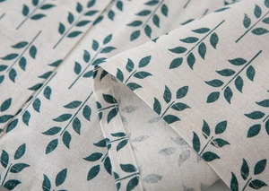 Close-up of linen fabric texture with green leaf print and fine stitching edges