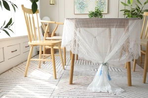 Détail de nappe en dentelle blanche avec pompons bleus sur une table en bois