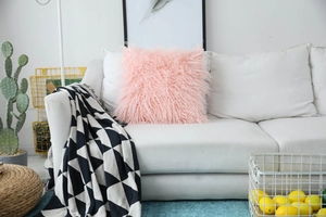 Detail of soft bright pink faux fur pillow cover on a modern white minimalist sofa