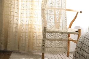 Gros plan d'un rideau en dentelle au crochet beige avec des motifs géométriques ajourés