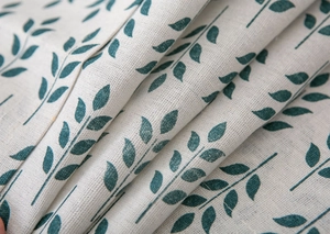 Close-up of linen fabric texture showing green leaf pattern and natural fiber weave