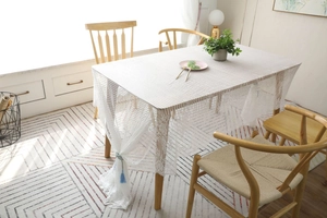 Détail d'une nappe en dentelle blanche avec motifs évidés et pompons bleu clair élégants