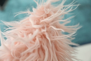 Macro shot of soft pink faux Mongolian sheepskin pillow cover with long fluffy texture