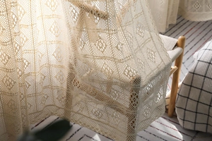 Vue détaillée du tissu en dentelle crochetée beige avec des motifs floraux évidés