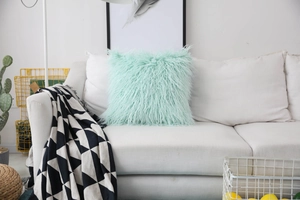 Detail of soft mint green faux sheepskin plush pillow on a white minimalist sofa