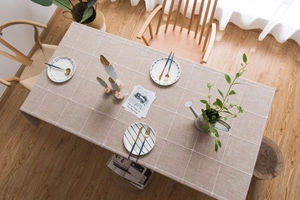 Close-up of Nordic style beige plaid linen tablecloth on a rustic wooden dining table
