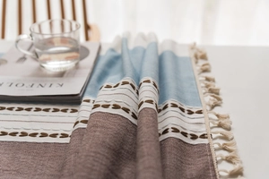 Detail of Nordic linen tablecloth with blue stripes, floral embroidery and tassel fringe
