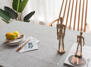 Detail of grey Nordic cotton linen tablecloth with white cross-stitch on a dining table