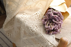 Détail de rideau en dentelle crochetée beige avec motifs floraux ajourés
