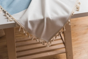Close-up of blue and white woven tablecloth with rustic textures and cream fringe detail