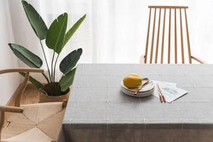 Detail of grey cotton linen tablecloth with white grid embroidery on rectangular table
