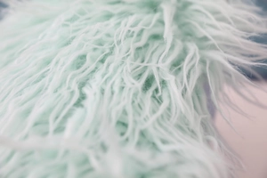 Macro shot of soft faux sheepskin long fur fabric in mint green for cushion covers