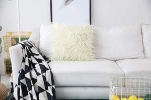 Detail of white faux sheepskin pillow cover texture on a sofa with modern home decor