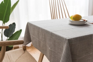 Detail of grey Nordic cotton linen tablecloth with white grid pattern and elegant drape