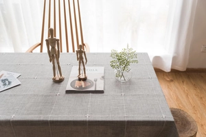 Detail of grey and white checkered linen tablecloth with delicate cross-stitch embroidery