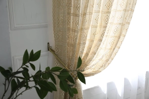 Gros plan d'un rideau au crochet rétro avec pompons tissés en blanc crème