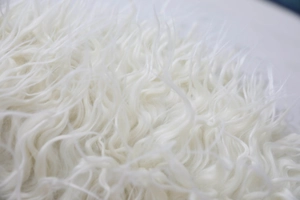 Detailed close-up showing soft white faux sheepskin curly texture on the cushion cover