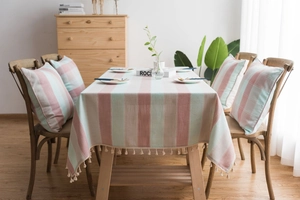 Detail of green striped waterproof tablecloth with elegant fringe tassels and matching cushion