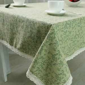 Detail van gebloemd groen tafelkleed met witte kantrand en rustieke linnen textuur