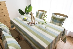 Close-up of mint green striped linen tablecloth with decorative tassel edges and matching cushion