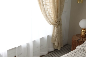 Détail d'un rideau au crochet rétro avec motifs ajourés et voilage blanc semi-transparent