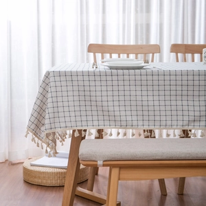 Minimalist blue checkered linen tablecloth with decorative tassels on a wooden dining table