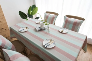 Close-up of pink and green striped waterproof tablecloth with beige tassel fringe detail