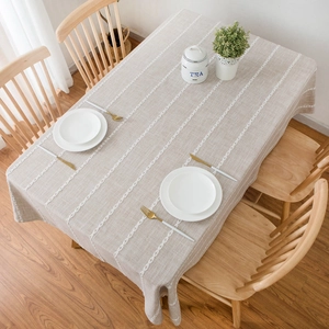 Detailed texture of beige linen tablecloth with vertical white lace embroidery stripes