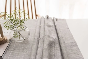 Detailed texture of gray linen table runner with white stitching on a wooden dining table